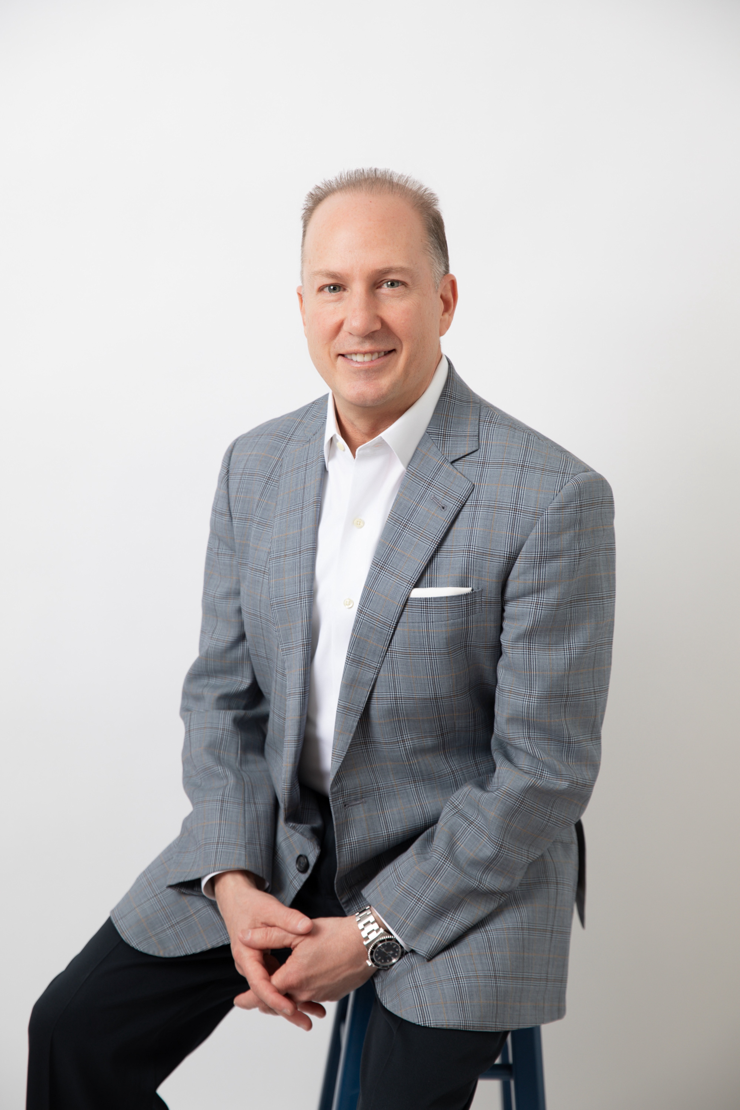 Greg Woods seated in a grey checked jacket